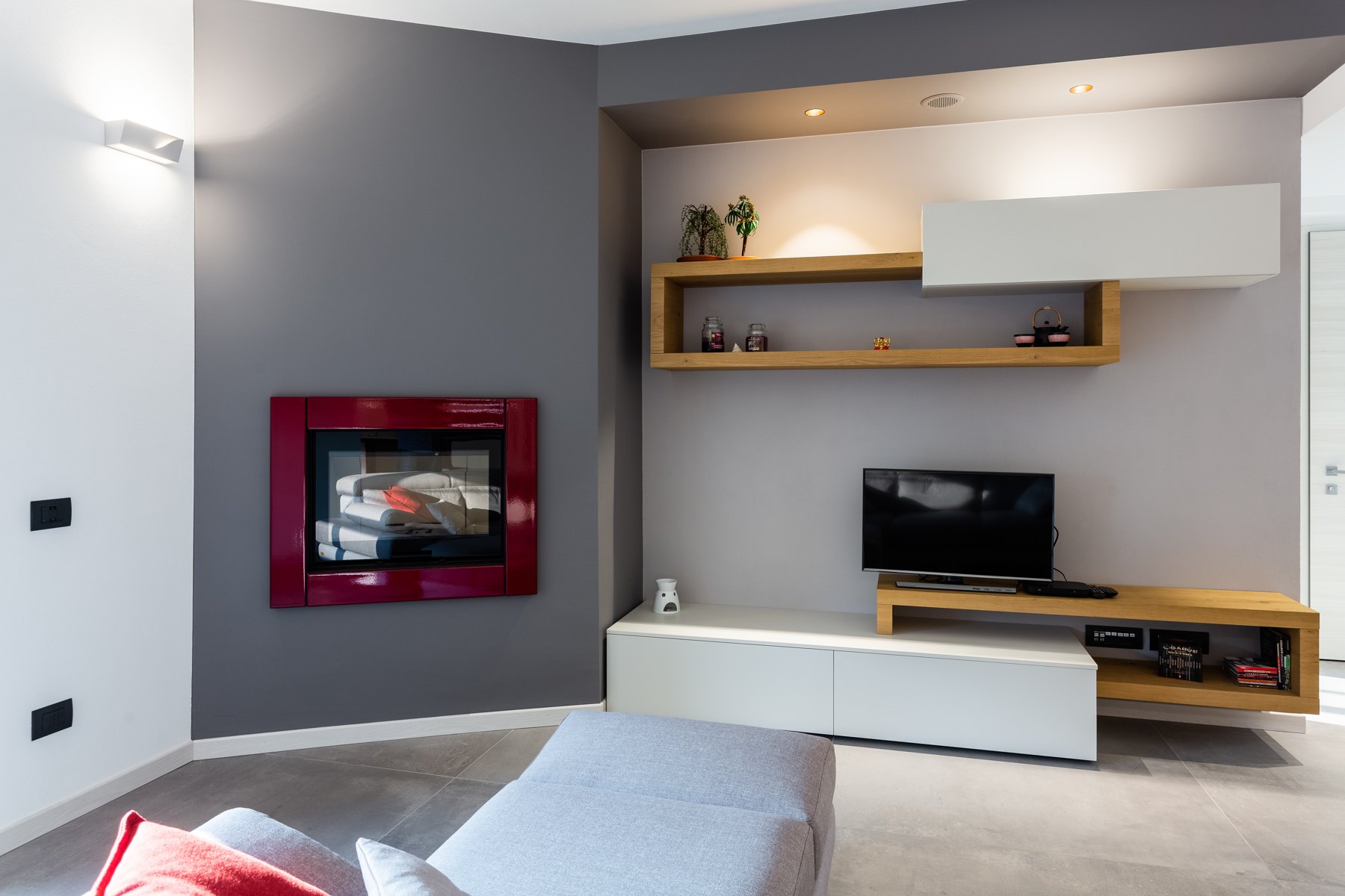 Soggiorno con mensole in legno e mobile TV sospeso — Giovanni Conti Interior Design