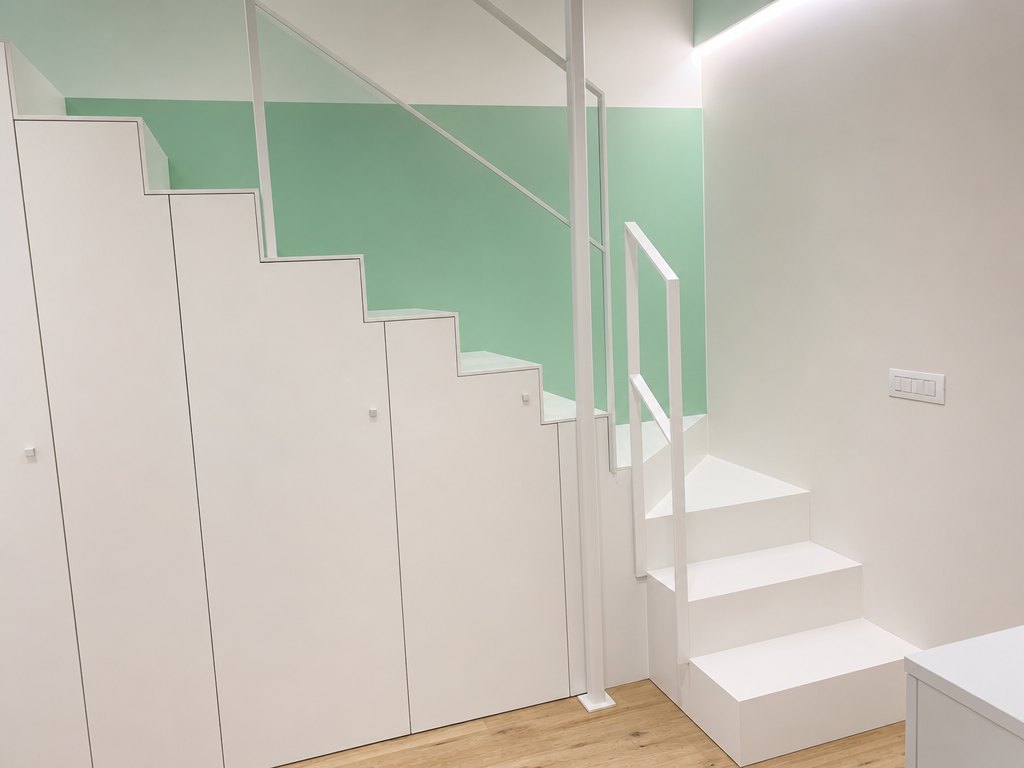 Armadiatura sottoscala su misura con ante sagomate sulla pendenza — Giovanni Conti Interior Design